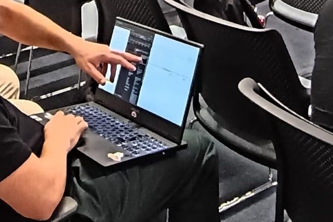 Close crop of a CTF player's hands on a laptop keyboard while a teammate points at the screen
